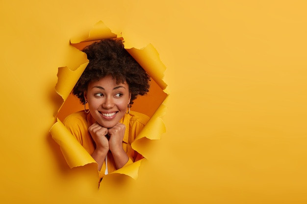 pretty cheerful woman holds both hands under chin