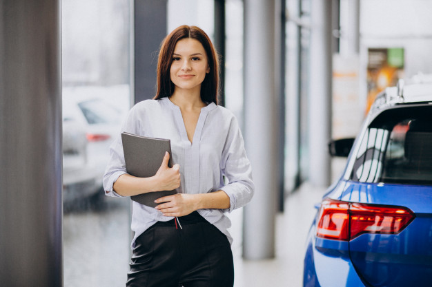 Young woman in a car showroom choosing a car